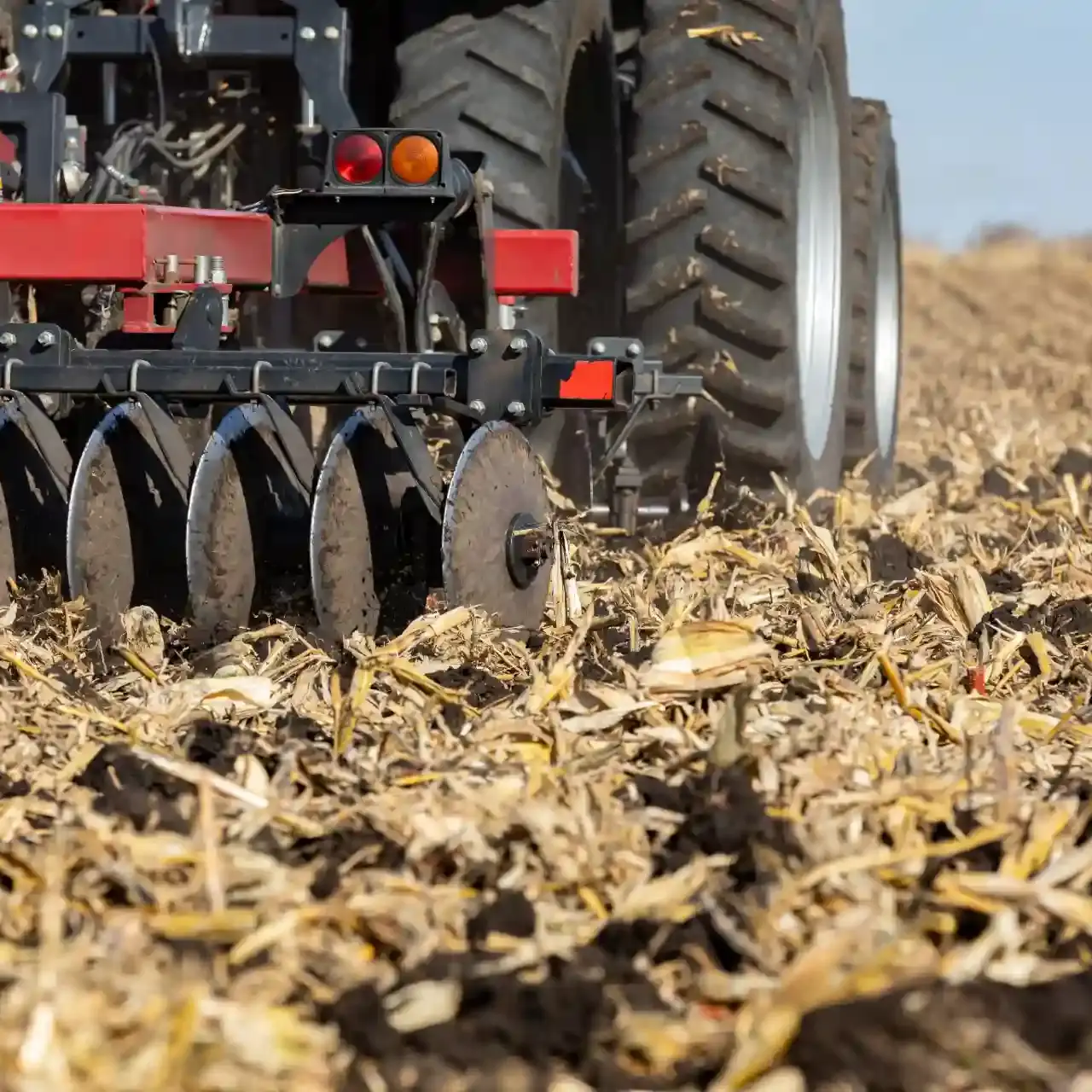 Implemento agrícola com discos (possivelmente uma plantadeira ou grade) trabalhando sobre a palhada seca.
