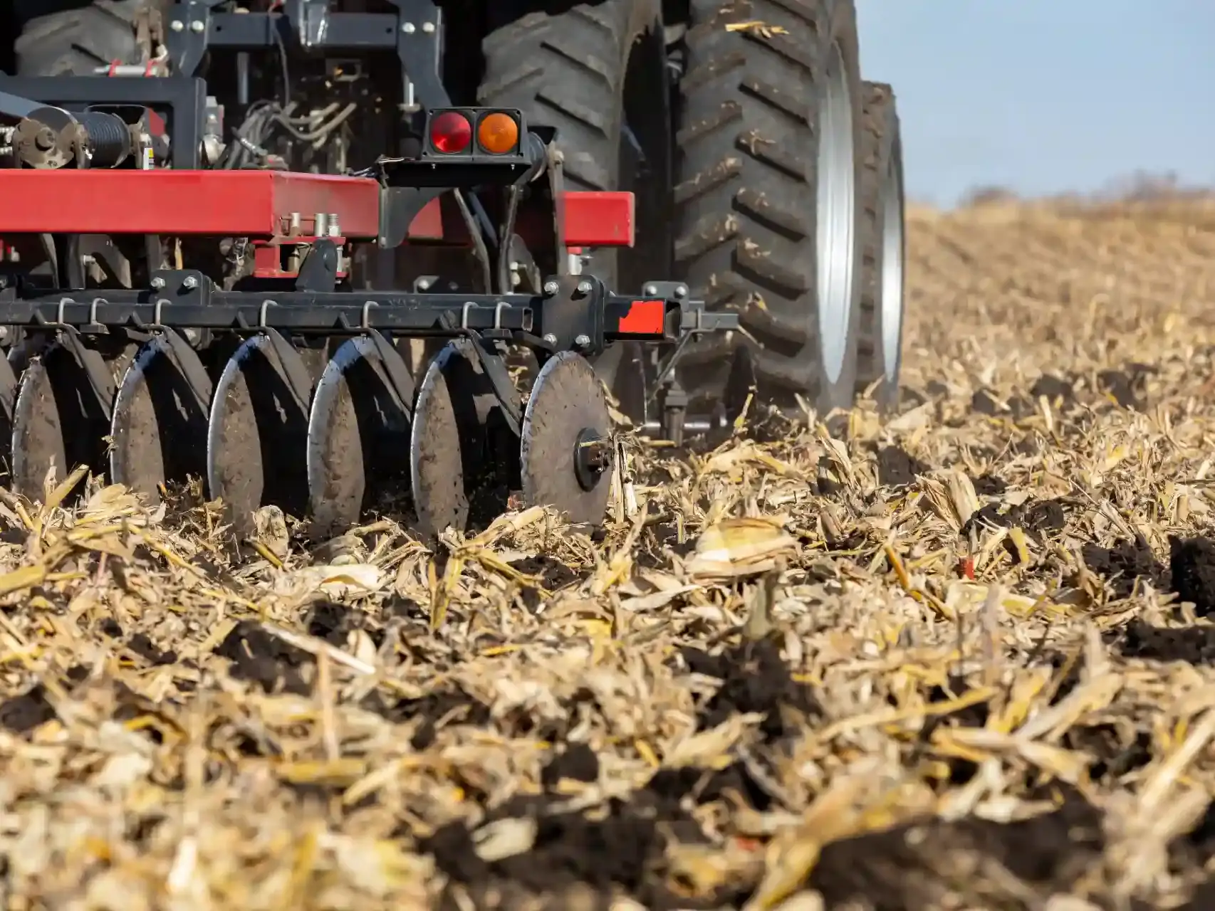 Implemento agrícola com discos (possivelmente uma plantadeira ou grade) trabalhando sobre a palhada seca.